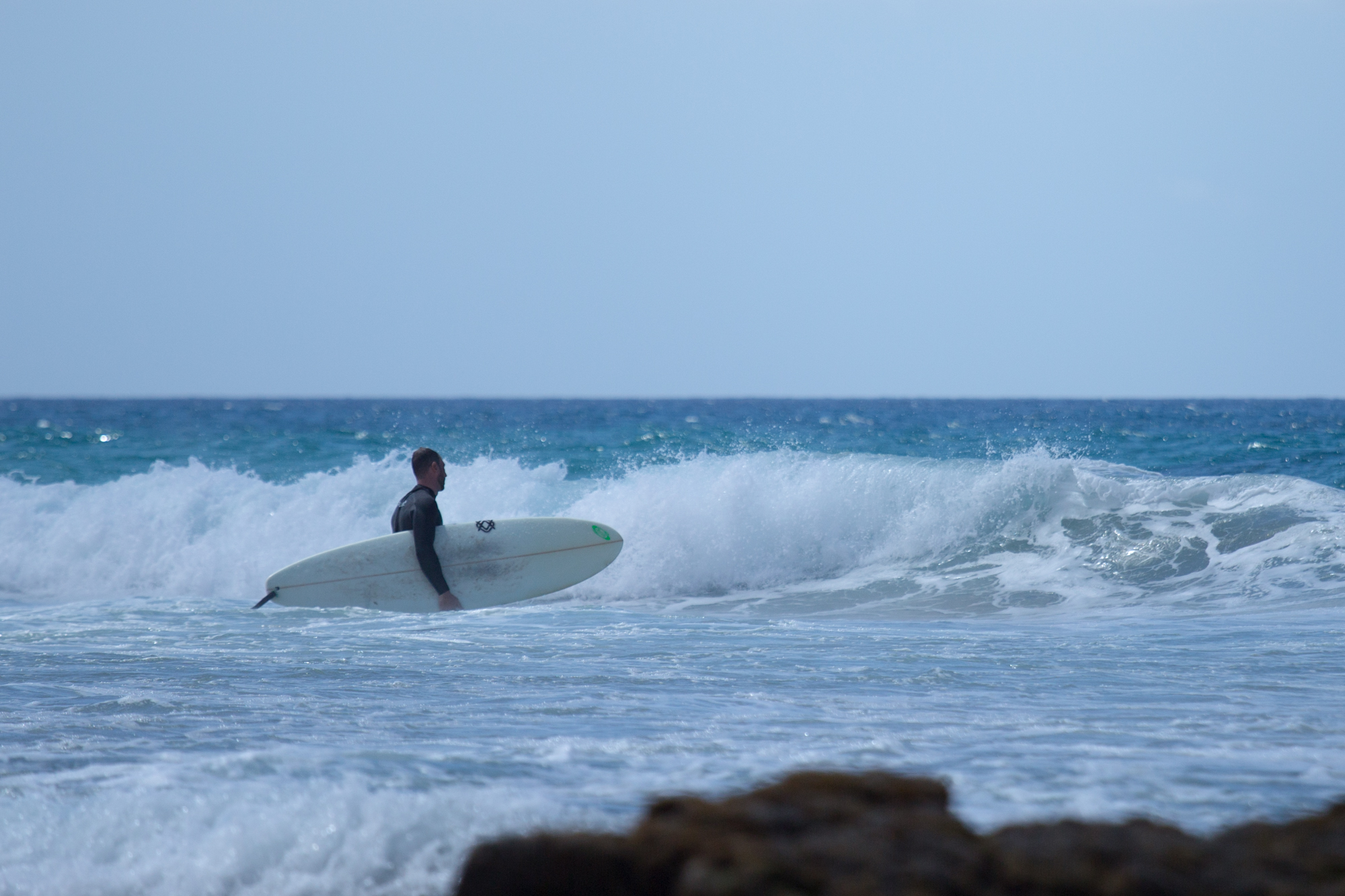 Surfer heading into the waves surf spot Fuerteventura