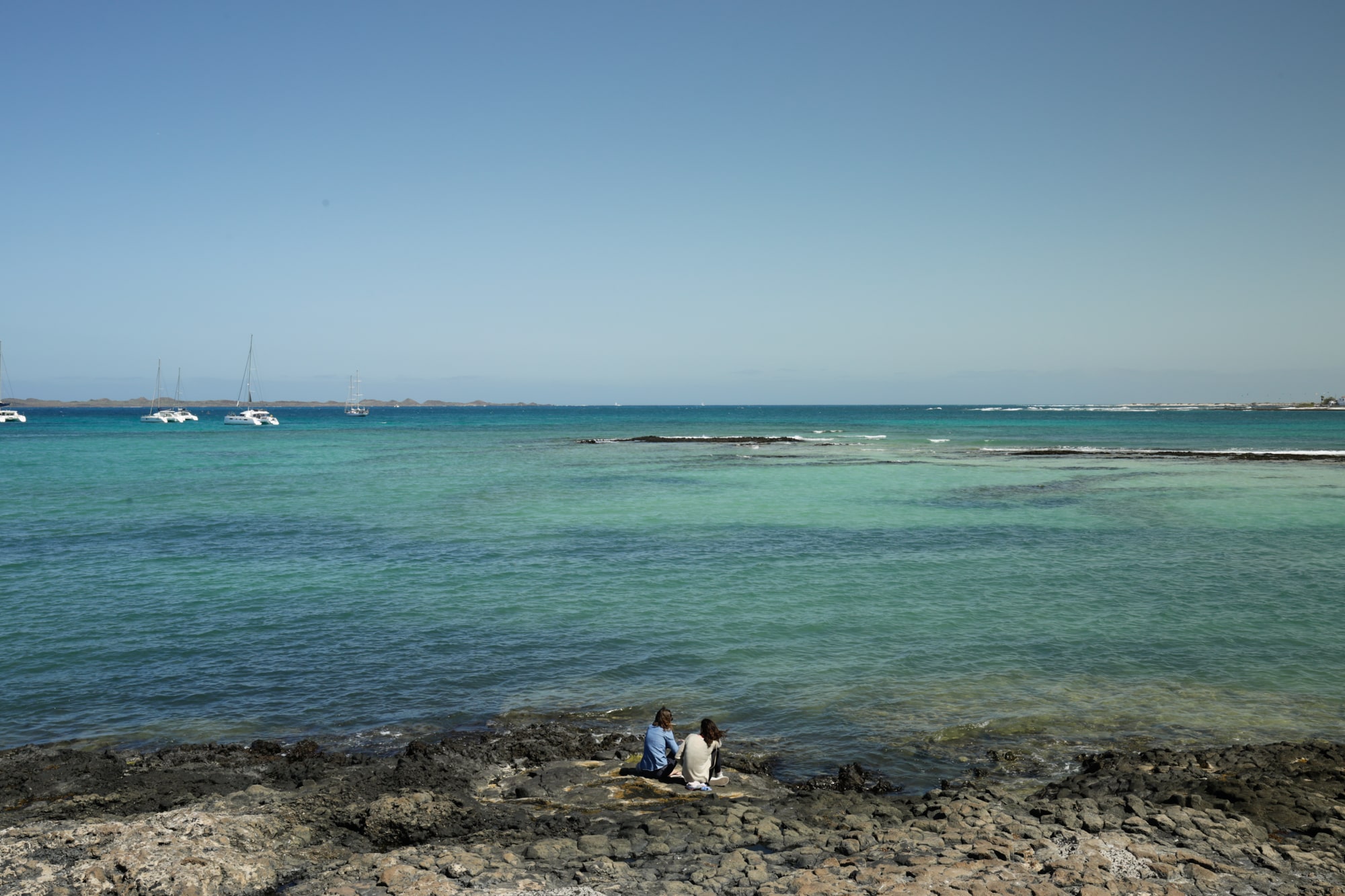people sitting by the ocean fuerteventura