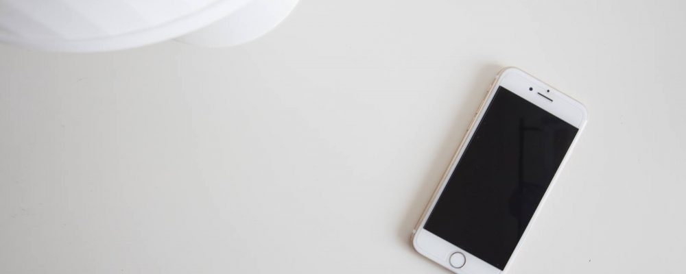 Top down view of an Iphone on a white desk