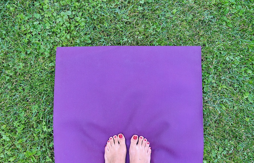 Yogi feet on a travel yoga mat on grass
