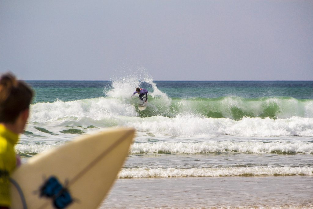 Surfer on the beach watching another surfer at Watergate Bay, Newquay