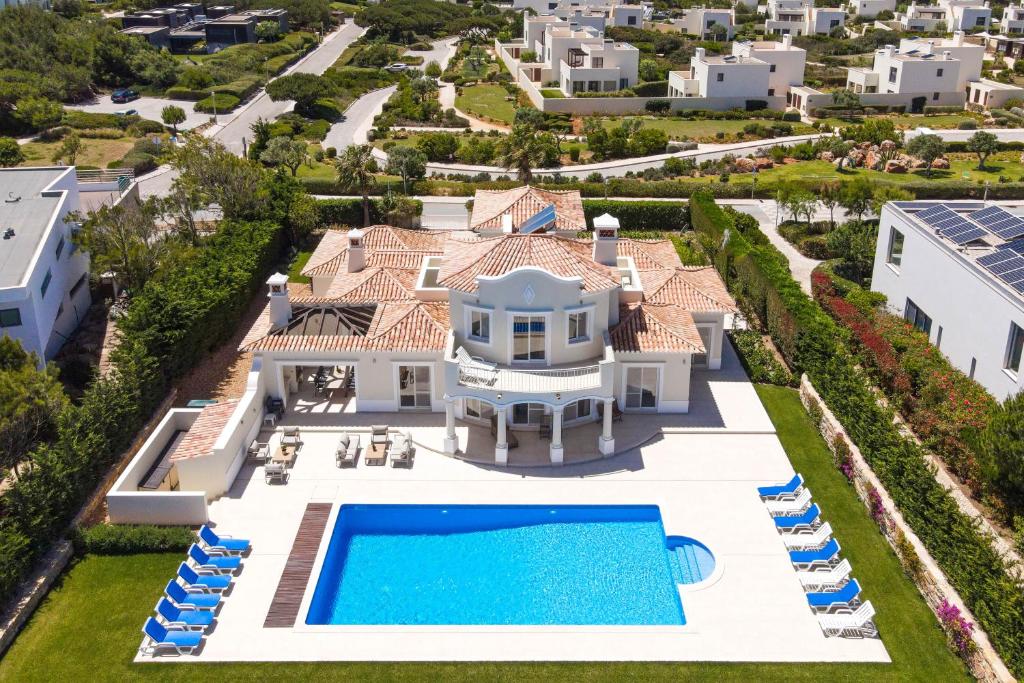 A bird view shot of a villa and a swimming pool with blue loungers placed on each side.