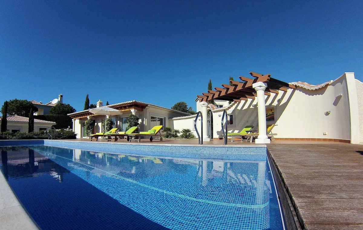 An image taken from the corner of a swimming pool with a luxury villa in the background. It's a beach front property on a beach in Sagres.